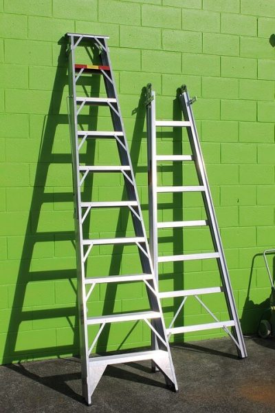 two ladders leaning on a green wall